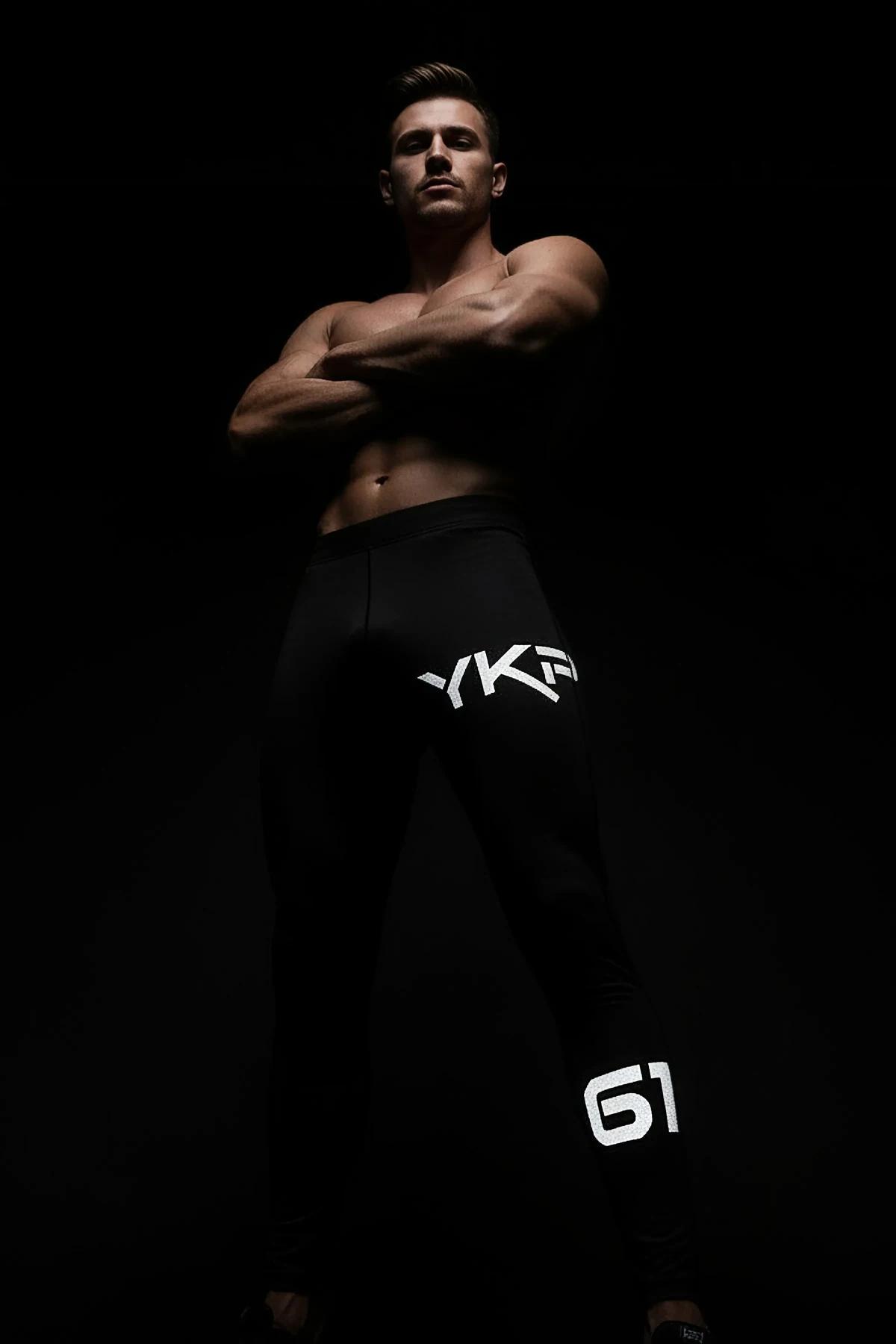 full-length black sport joggers with reflective branding in low-light setting
