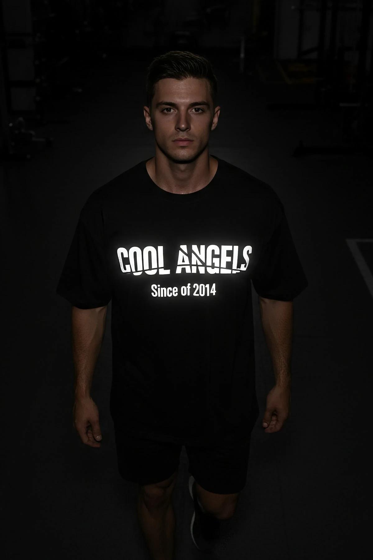 black oversized glow-in-the-dark reflective t-shirt with bold COOL ANGELS Since of 2014 chest graphic lit in low light