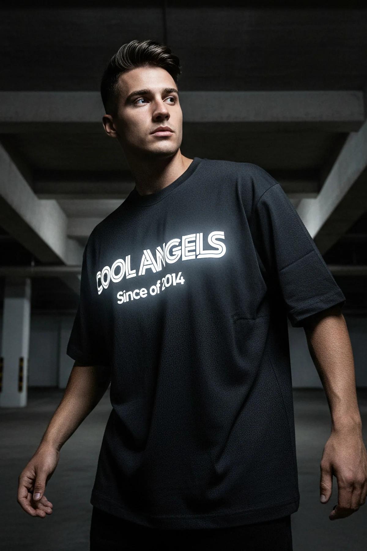 black oversized glow-in-the-dark reflective t-shirt with bold COOL ANGELS Since of 2014 chest graphic lit in low light