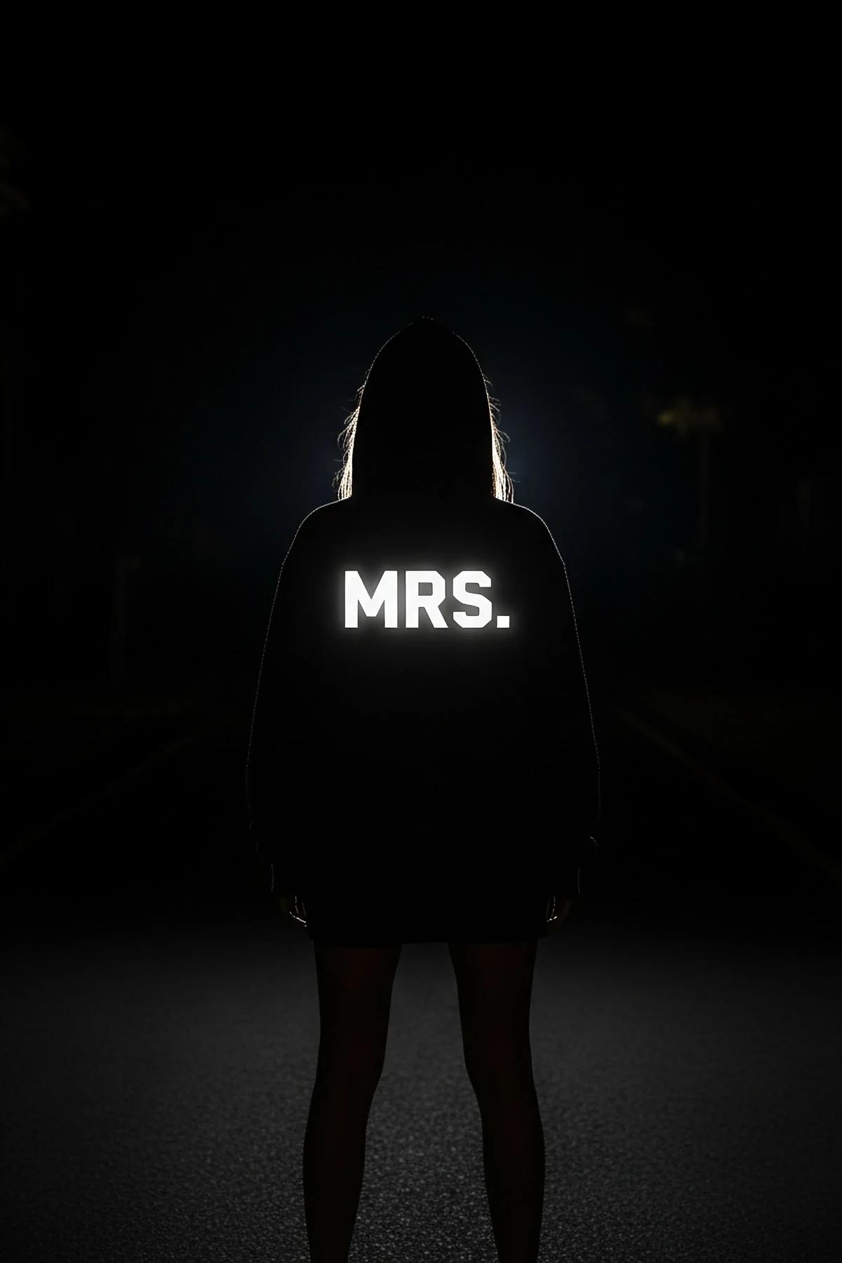side profile of oversized black Mrs. hoodie worn as mini dress length with reflective print activated by flash