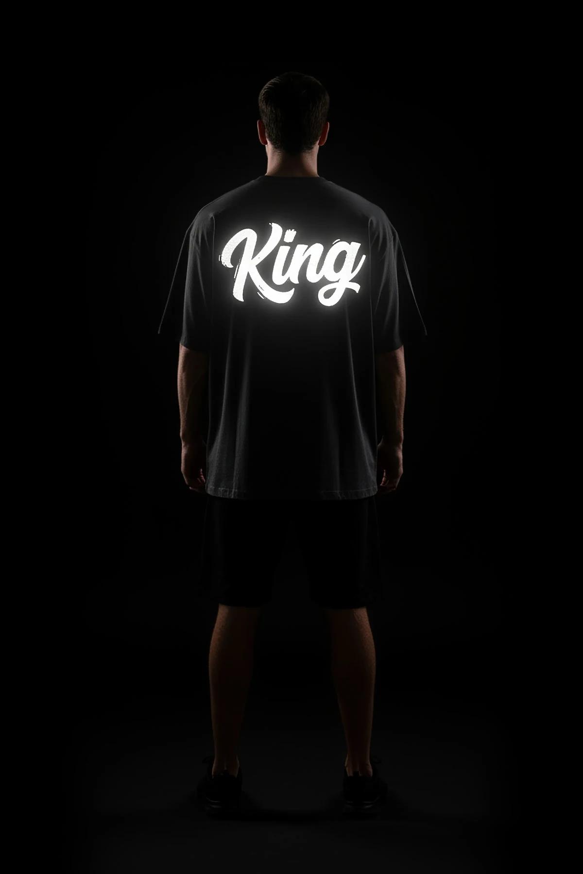 black oversized t-shirt back view with white retroreflective brush-script custom text graphic glowing in low light
