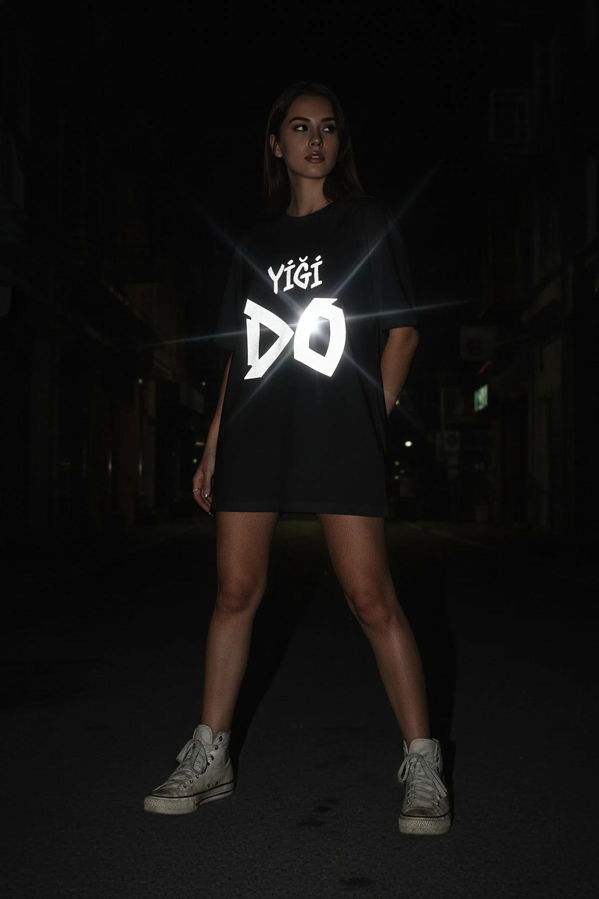 oversized black graphic tee with bold display-style lettering worn in low-light environment