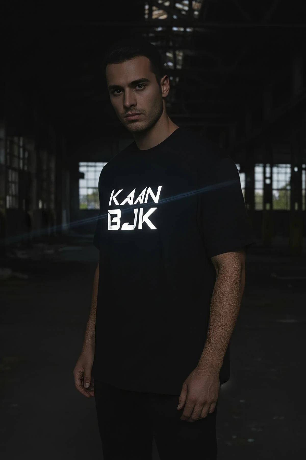 black oversized reflective logo t-shirt with glowing white chest graphic on male model in dark warehouse