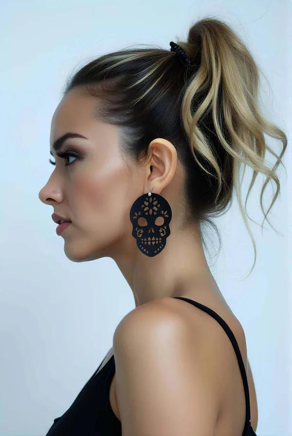 Black faux leather skull dangle earrings with laser-cut floral cutwork worn on pierced ear side profile view