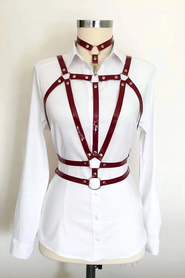 Crimson patent faux leather halterneck body harness with silver O-rings and stud rivets displayed on mannequin over white shi