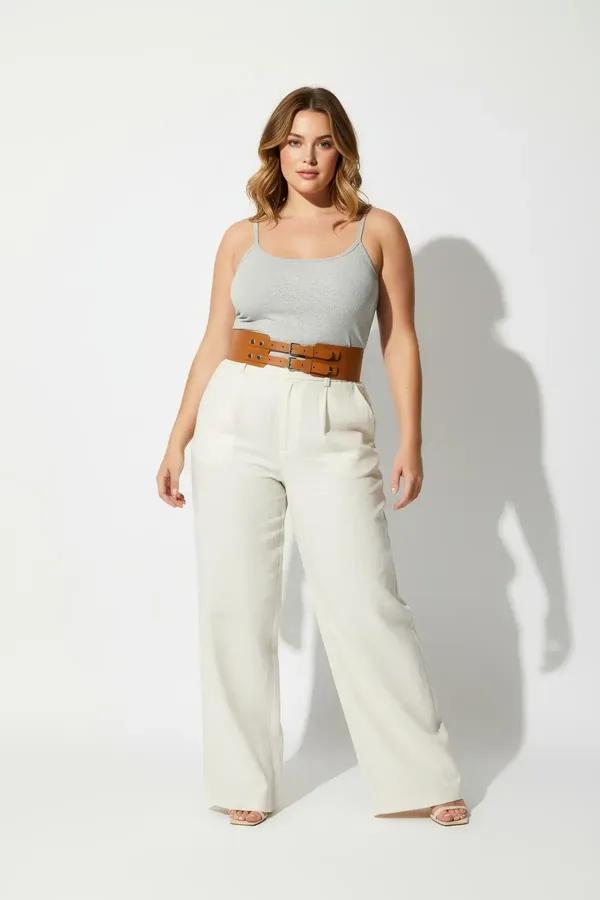 wide tan faux leather corset belt with double silver buckles worn over white tank and linen trousers