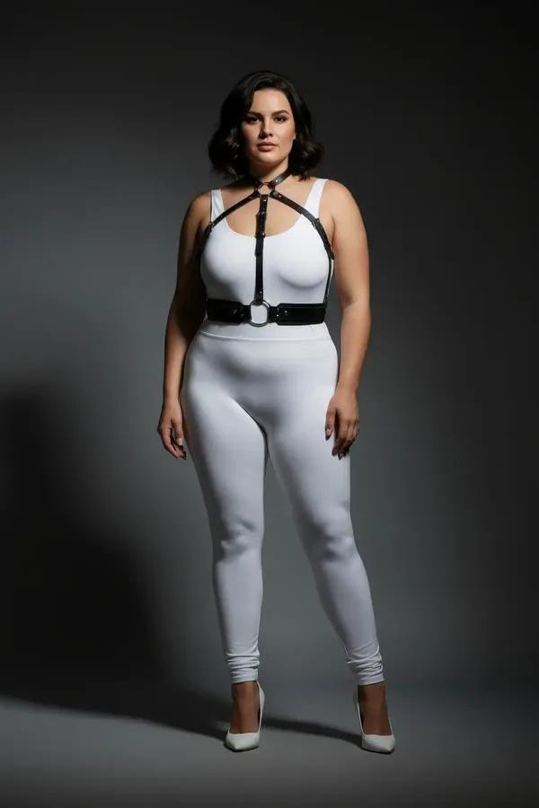 black faux leather strappy chest harness with silver O-ring underbust closure worn over white outfit plus size model