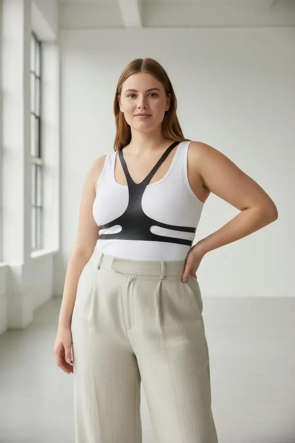 black faux leather chest harness overlay with V-front straps and dual waist bands worn over white tank top