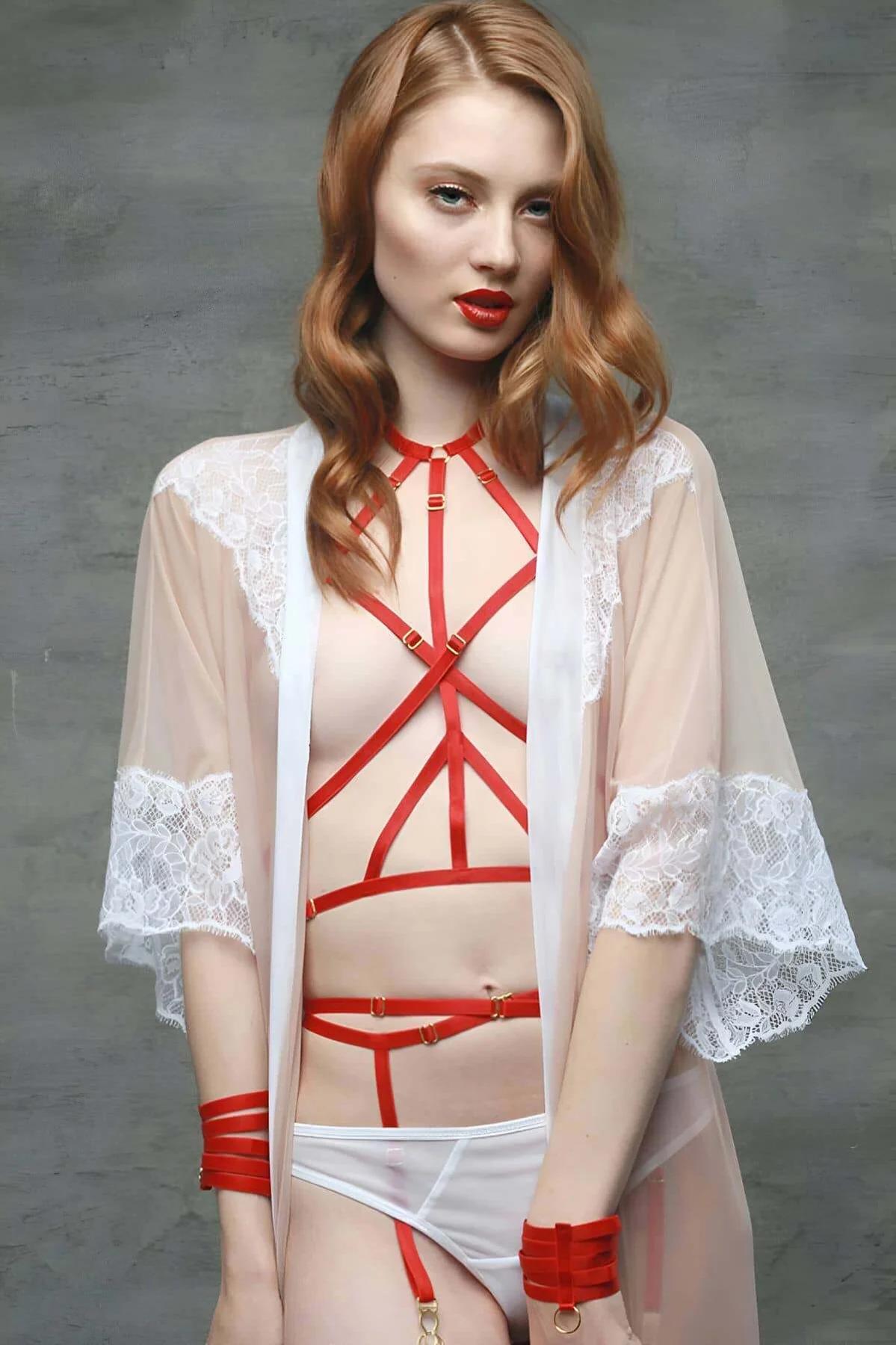 Close-up of gold-tone O-ring and slider buckles on red elastic body harness