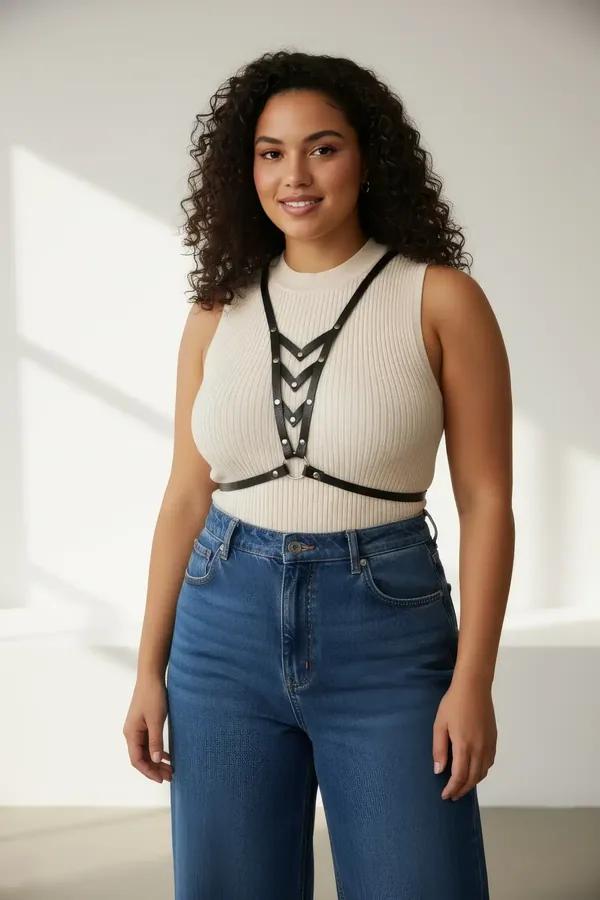 Black faux leather v-neck chest harness with cascading interlinked silver O-rings worn over cream knit top