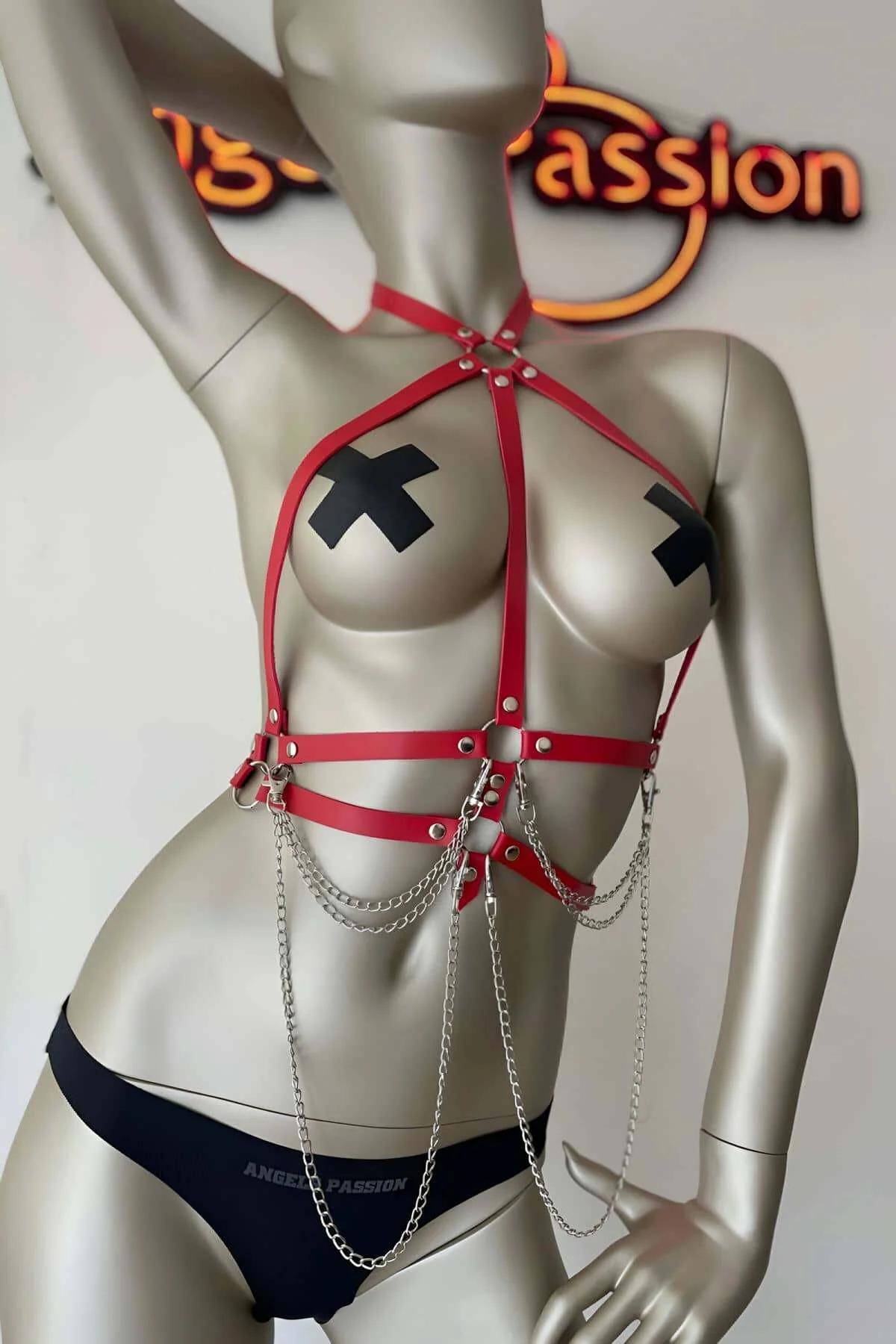 Silver draping chain segments on red chest harness, close-up detail of lower strap tier