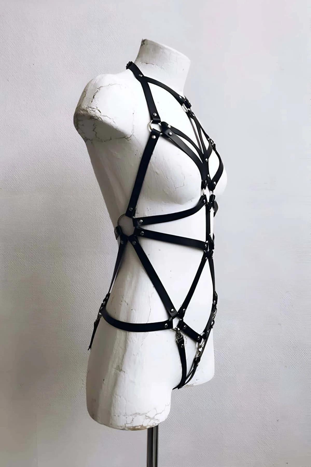 Detail shot of silver stud hardware at strap crossings on black faux leather body cage harness