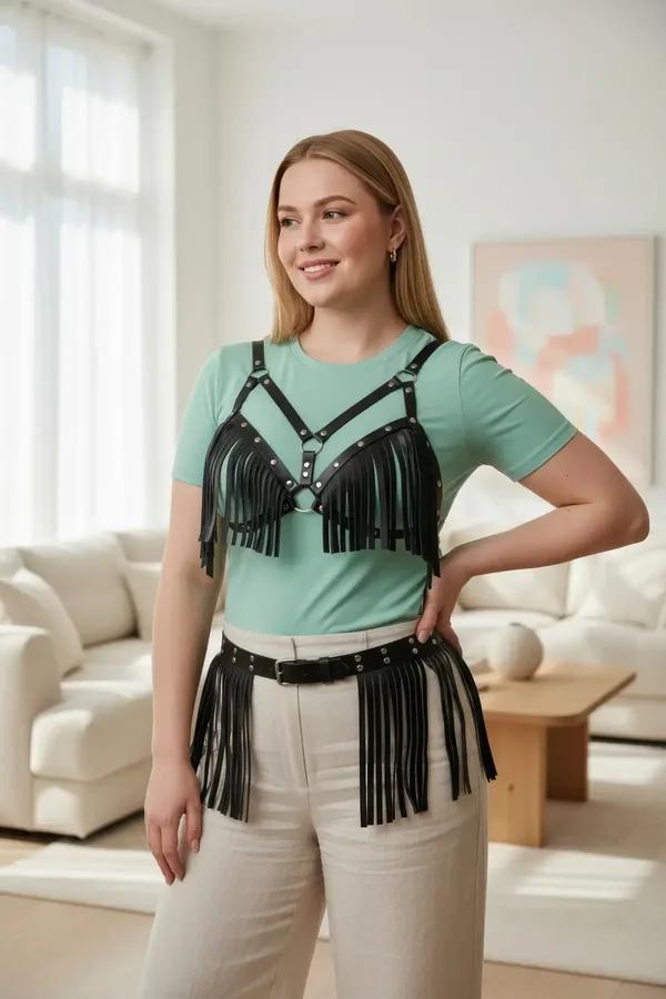 black faux leather fringe chest harness with O-ring and silver studs worn over white top with matching fringe waist belt