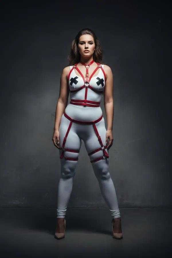 red faux leather strappy body harness set with garter thigh straps and gold O-ring buckles, worn by plus-size model