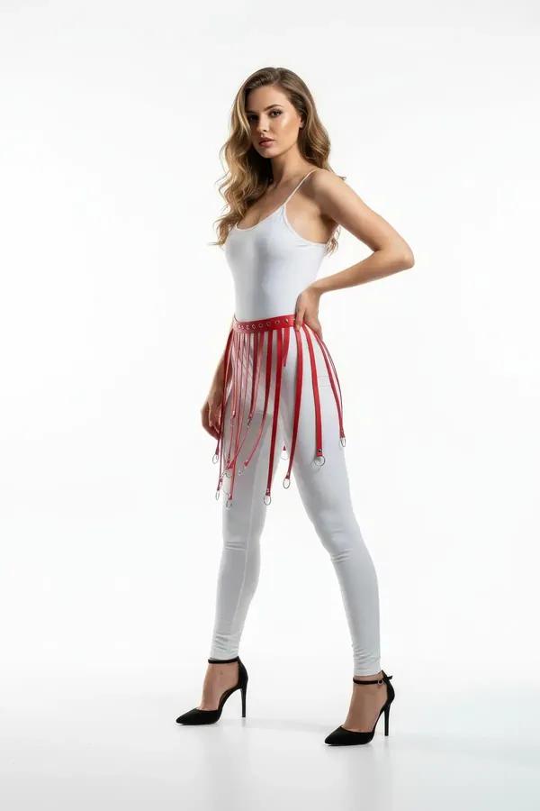 red faux leather waist harness with silver O-ring fringe straps worn over white leggings and bodysuit