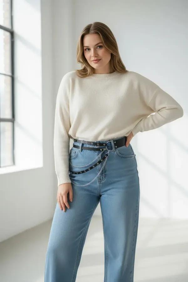 black faux leather double-row studded belt with silver O-ring and cascading chain drapes worn at waist over cream knit sweate