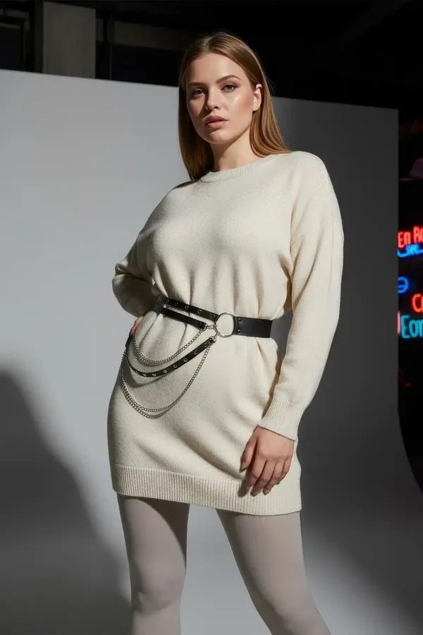 black faux leather double-row studded belt with silver O-ring and cascading chain drapes worn at waist over cream knit sweate