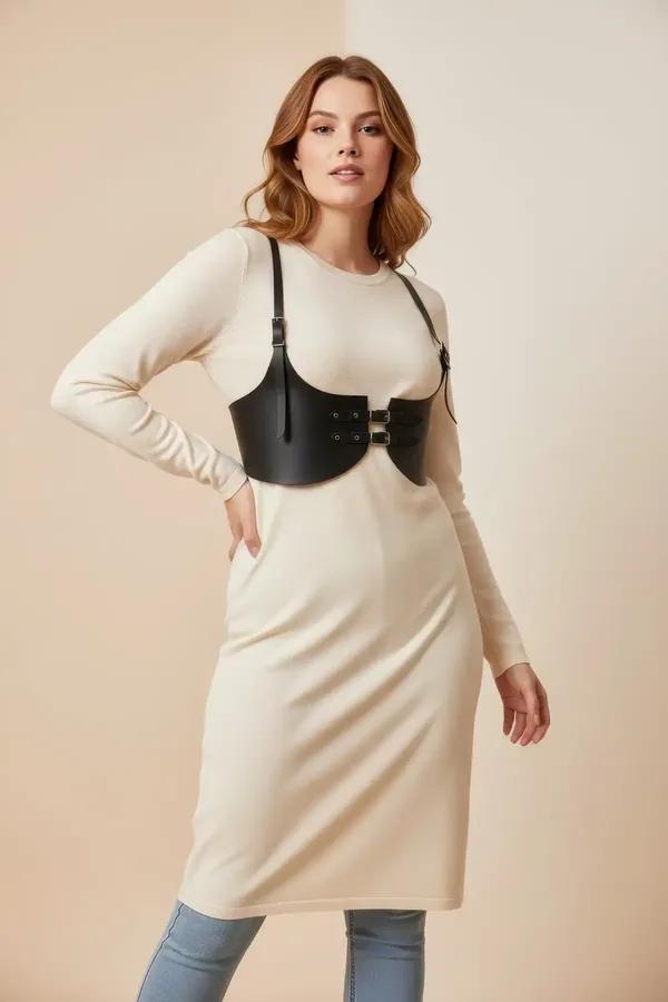 black faux leather underbust harness with wide straps and silver buckles worn over cream ribbed sweater