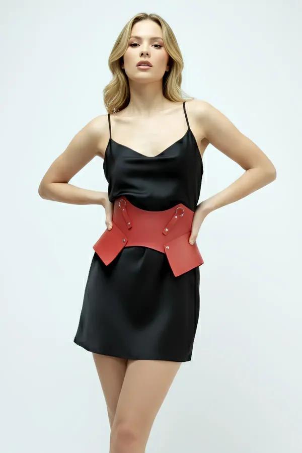 red faux leather corset waist cincher with gold studs worn over black satin slip dress