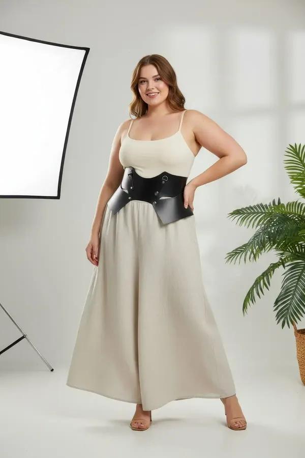 Black faux leather wide waist belt with sculptural wing panels and silver D-ring hardware worn over cream ribbed dress