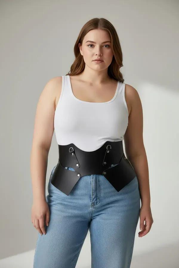 Black faux leather wide waist belt with sculptural wing panels and silver D-ring hardware worn over cream ribbed dress