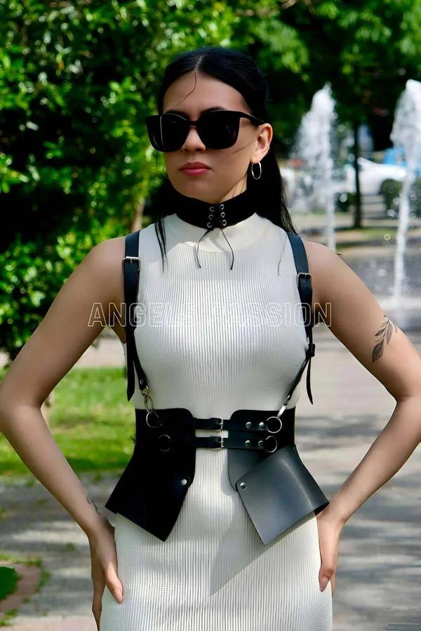 siyah suni deri vücut harness ve choker takım, gümüş O-ring ve tokalar, belde mini kılıf çanta, beyaz elbise üzerine giyilmiş