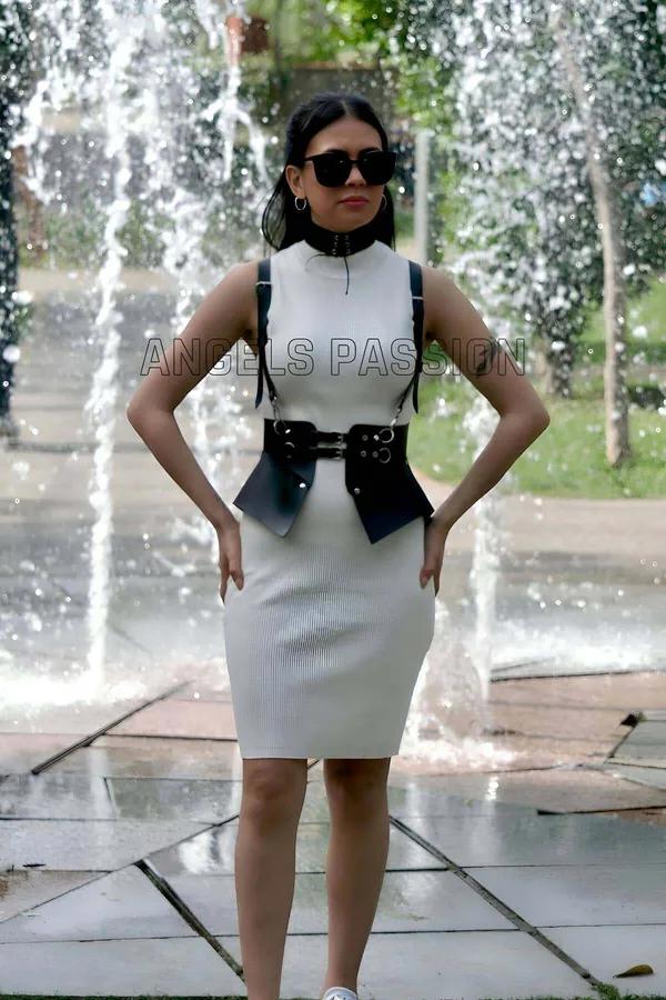 siyah suni deri vücut harness ve choker takım, gümüş O-ring ve tokalar, belde mini kılıf çanta, beyaz elbise üzerine giyilmiş