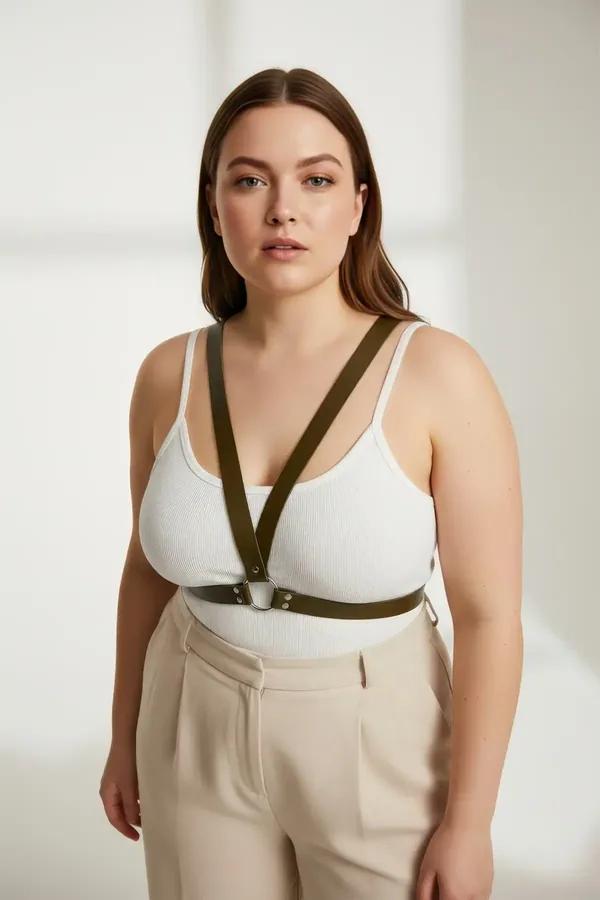 olive green faux leather o-ring chest harness with gold-tone hardware worn over white tank top plus size model