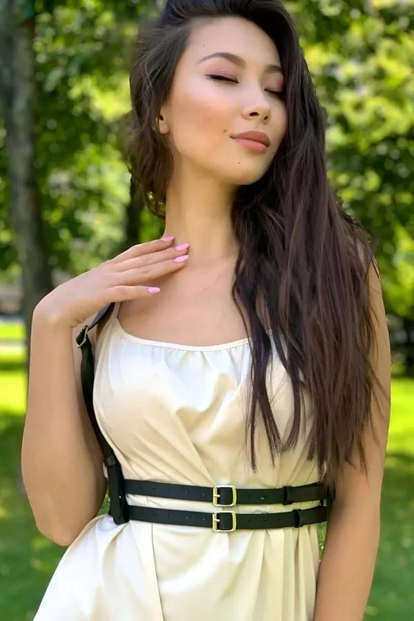 Siyah faux deri omuz askılı çift altın tokalı vücut harness kemer, krem saten elbise üzerinde