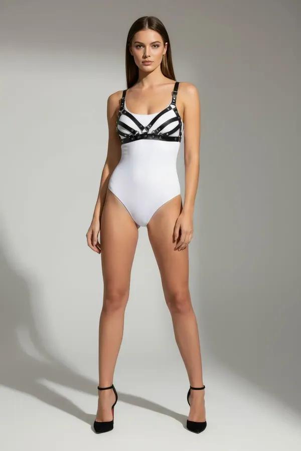strappy black faux leather chest harness with five horizontal bands and gold-tone stud rivets worn over white bodysuit