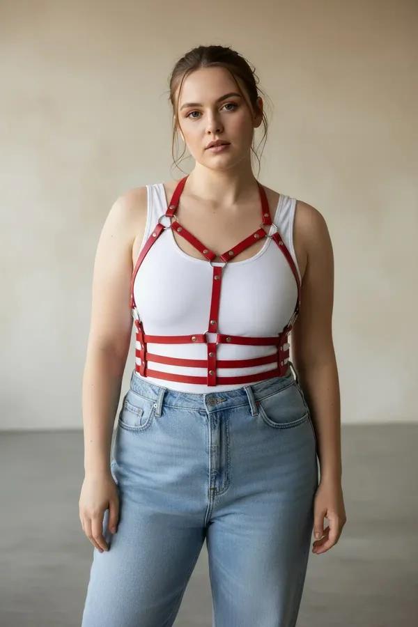 red faux leather strappy chest and waist harness with silver O-rings worn over white t-shirt