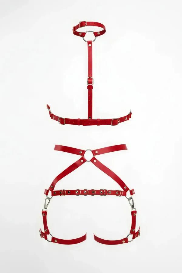 red vegan leather full body harness flat lay showing O-ring choker chest piece and X-cross garter lower piece with silver har