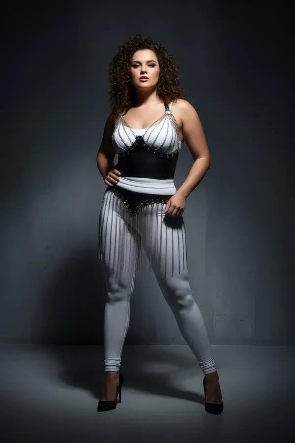 Black faux leather bustier with silver draped chain detail and matching chain fringe hip skirt set, worn over white bodysuit