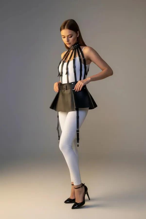 Black faux leather flared harness skirt with four adjustable silver-clip garter straps worn over white leggings