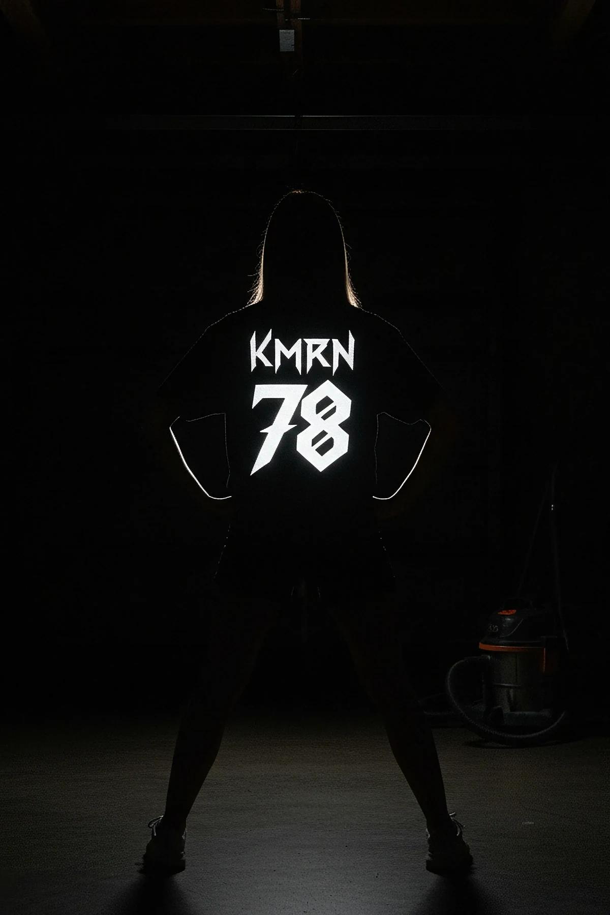 black reflective custom graphic t-shirt back view with bold gothic name and number print glowing white in low light