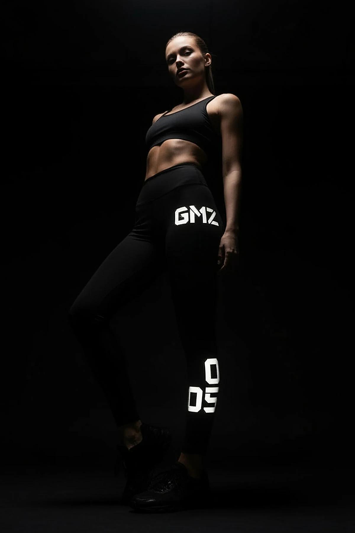 black high-waist performance leggings with white reflective letter print on outer thigh and calf full-length fit