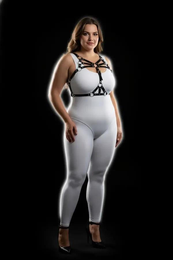 black faux leather strappy chest harness with silver O-rings worn over white bodysuit plus size model
