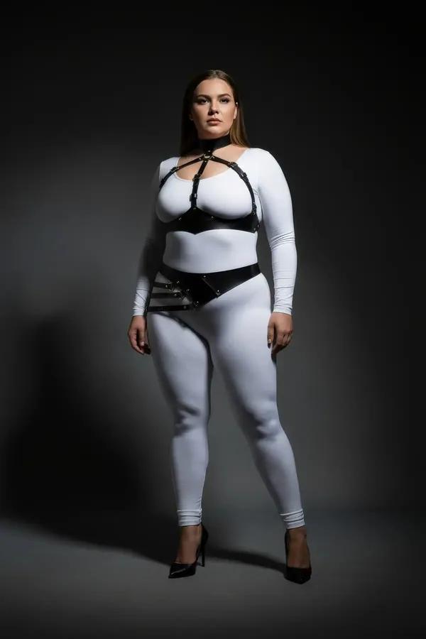black faux leather full body harness with chest cage collar and diagonal hip belt worn over white bodysuit plus size model