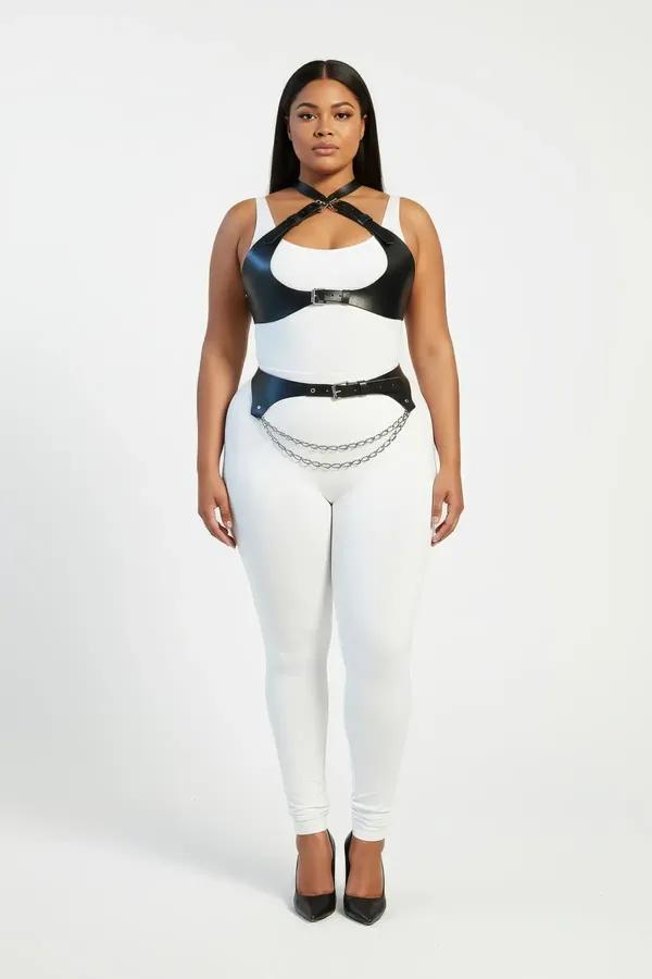 black faux leather harness set with cross-strap chest piece and layered silver waist chain belt worn by plus-size model