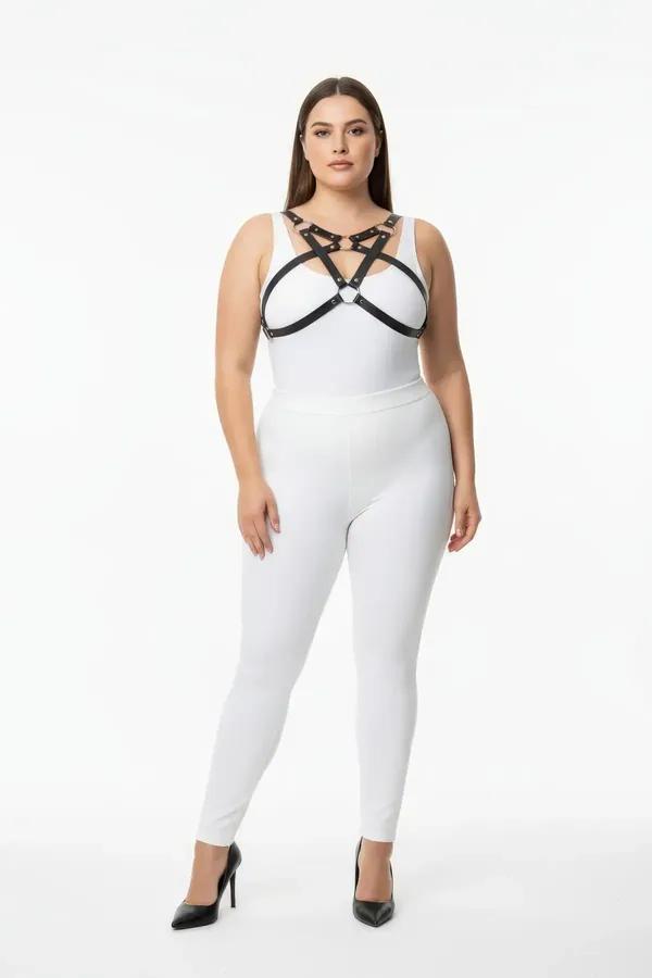 black faux leather chest harness with crossed straps silver studs and central O-ring worn over white outfit
