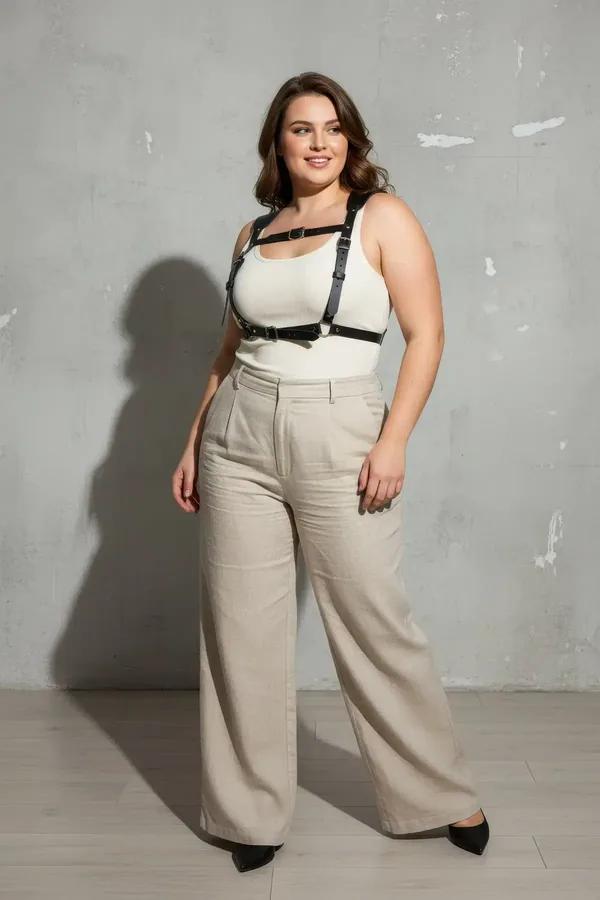 black faux leather caged chest harness with four silver-tone buckles worn over cream ribbed tank top plus-size model
