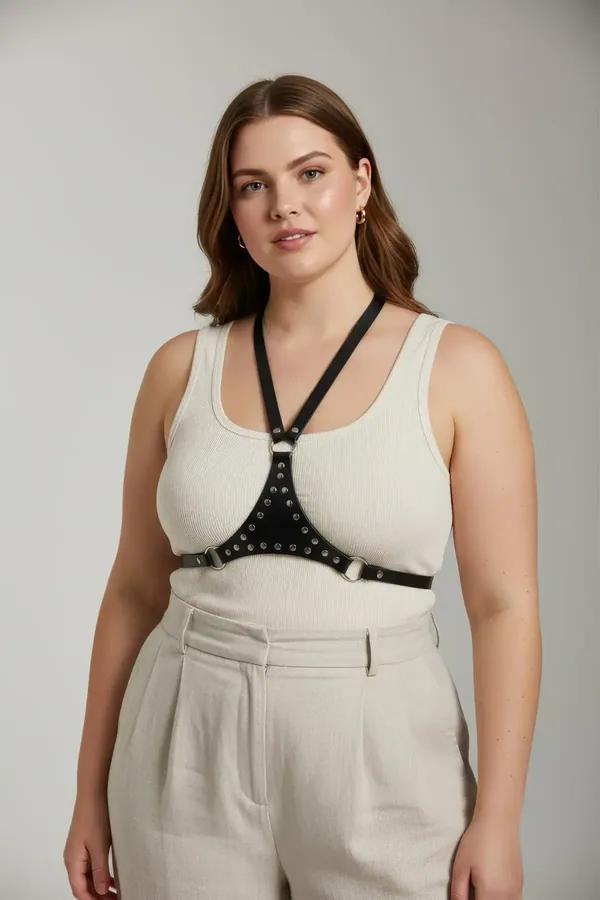 studded black faux leather chest harness with silver-tone studs and adjustable halter Y-straps worn over cream bodysuit