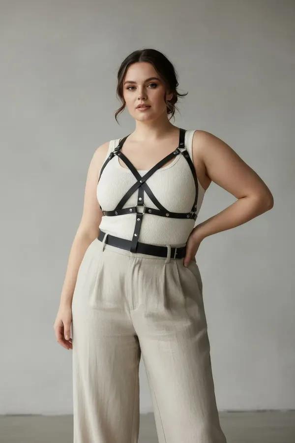 black faux leather x-strap chest harness with silver stud accents worn over white tank top, adjustable buckle closures