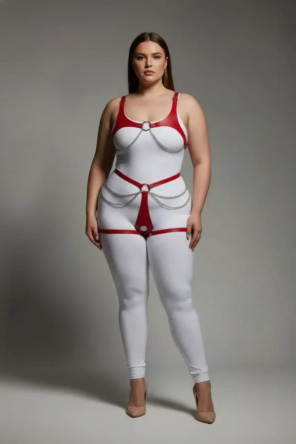 red faux leather body harness with silver O-rings and draped chain detail worn over white bodysuit, full-body front view