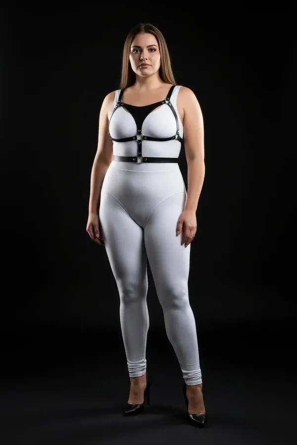 black faux leather strappy body harness with cage chest cutouts and silver O-ring hardware worn over white outfit