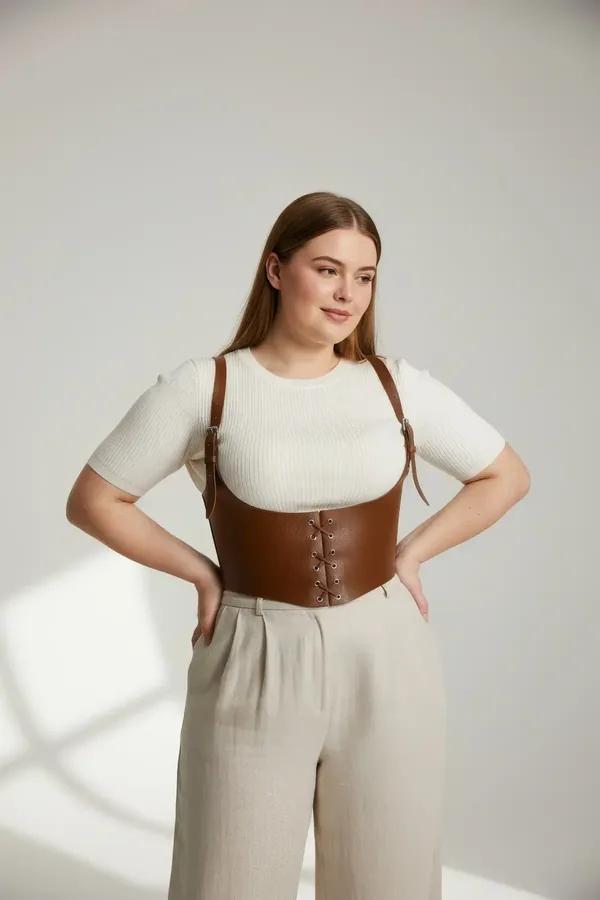 tan faux leather underbust corset harness with lace-up front and wide adjustable shoulder straps worn over white top