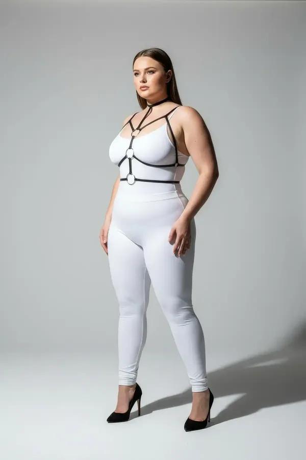 Black faux leather strappy chest harness with double gold O-rings and choker neck strap worn over white outfit