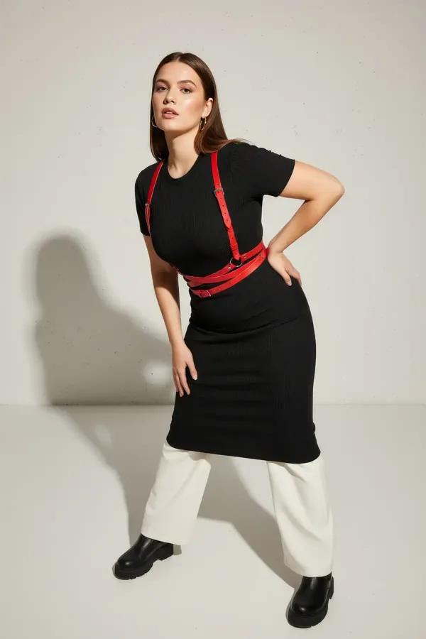 red faux leather criss-cross body harness with silver buckles worn over cream sweater