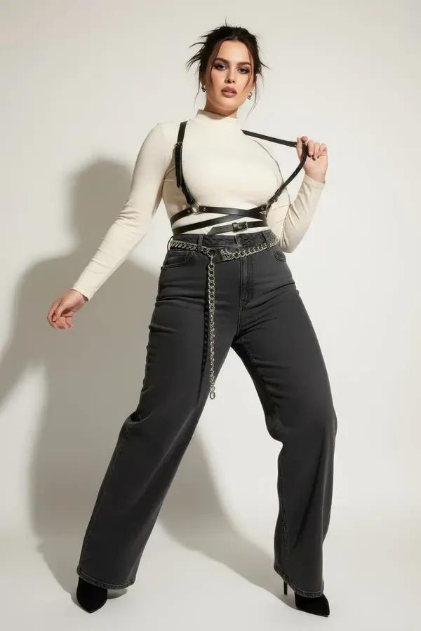 Black faux leather cross-strap underbust harness with criss-cross waist straps and silver buckles worn over white turtleneck