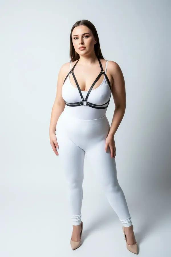 black faux leather chest harness with three silver O-rings worn over white bodysuit, minimalist strappy style